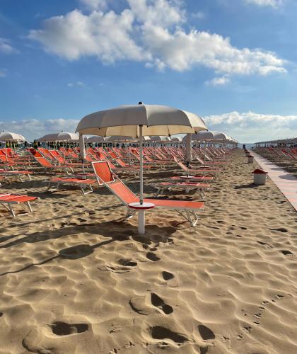Plage avec transats et parasols orange sous un ciel bleu.